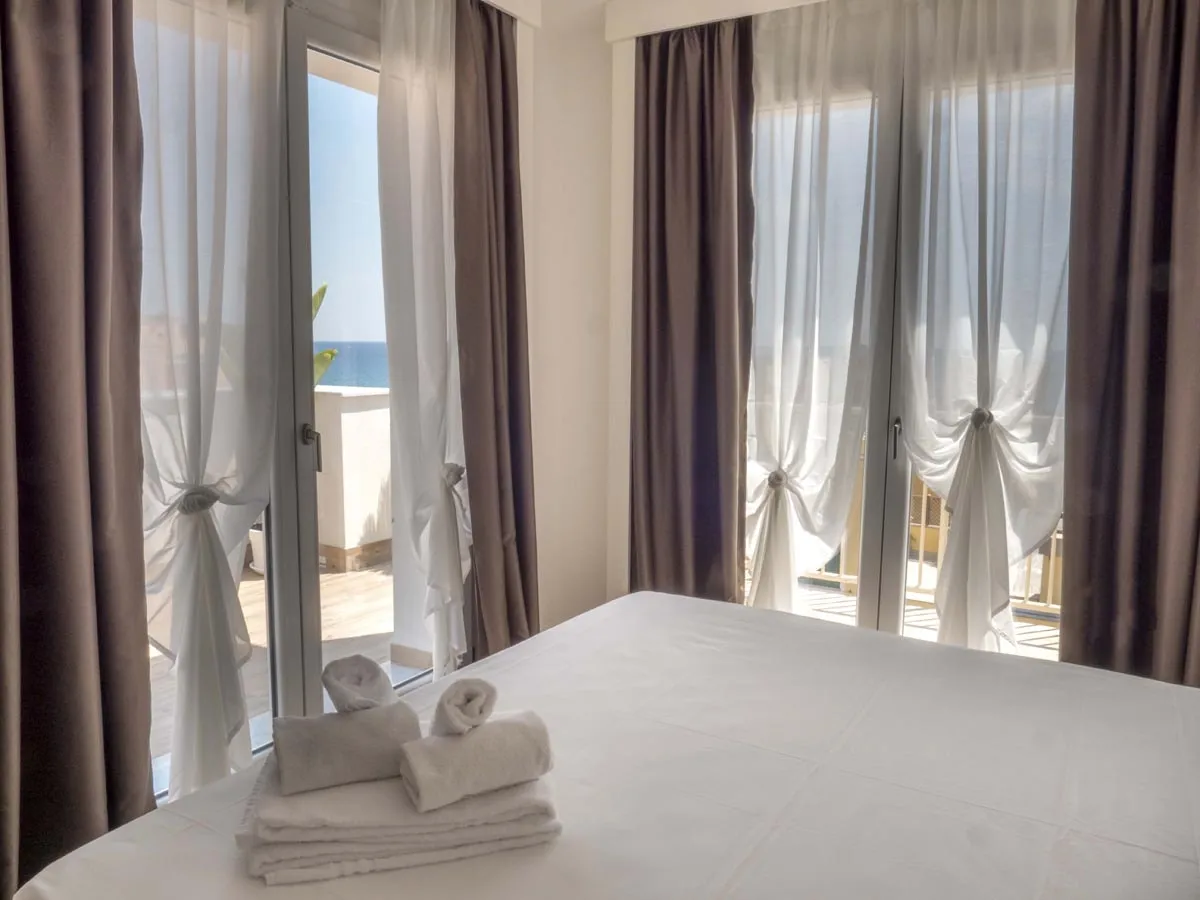 Camera con letto matrimoniale e ampie vetrate affacciate sul mare