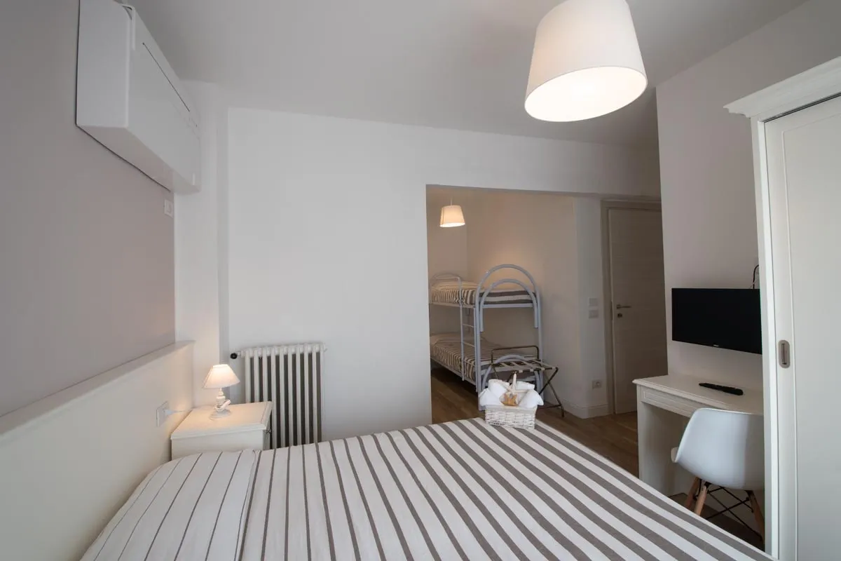 Camera con letto matrimoniale a righe e zona con letti a castello
