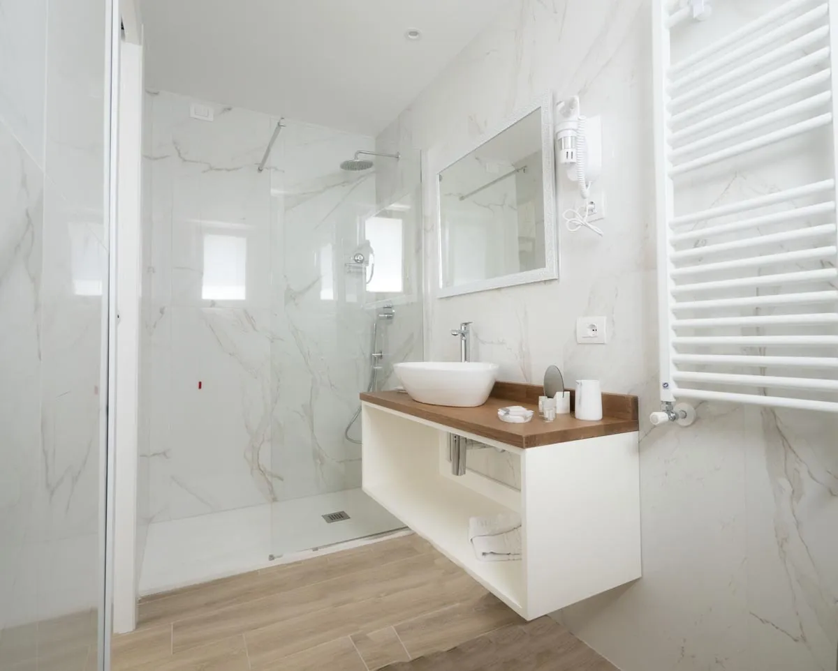 Bagno moderno in marmo con doccia, lavabo e scaldasalviette