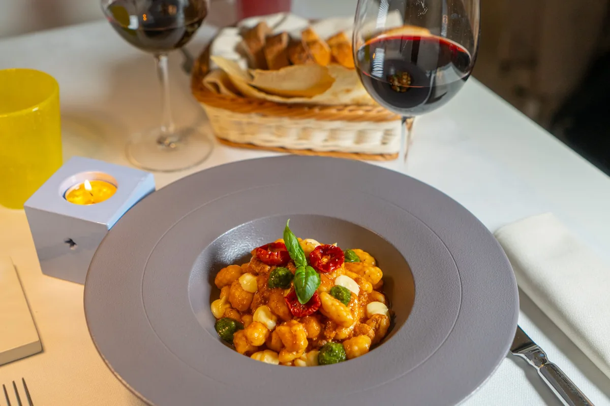 Piatto di gnocchi al pomodoro con basilico e vino rosso