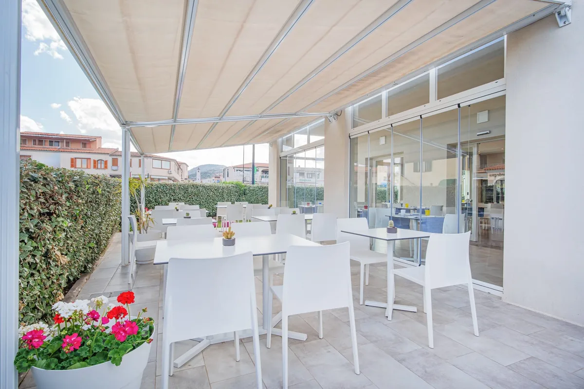 Terrazza esterna del ristorante con tavoli bianchi e fiori