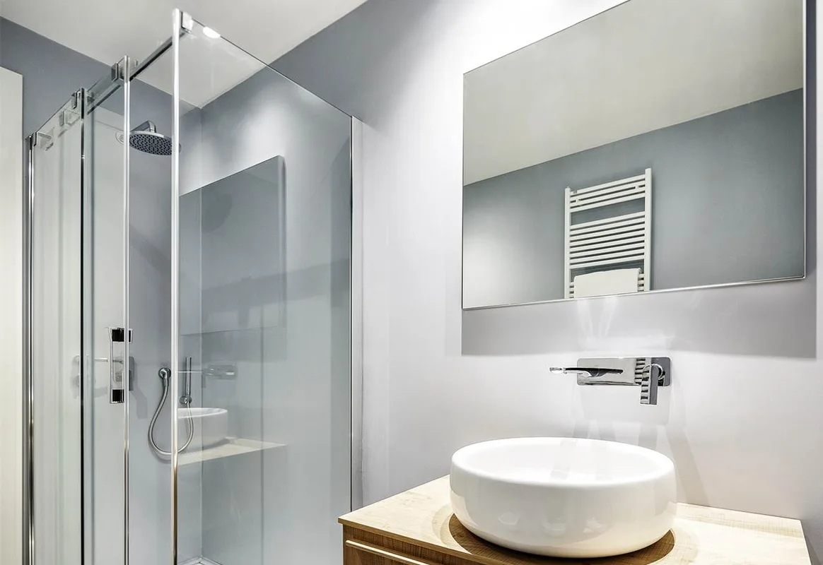 Bagno moderno con doccia in vetro e lavabo su mobile in legno