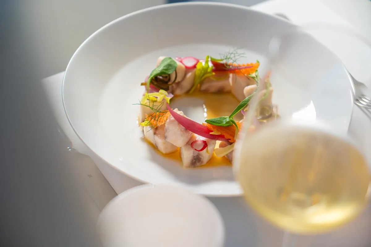 Piatto gourmet di pesce crudo con verdure e vino bianco
