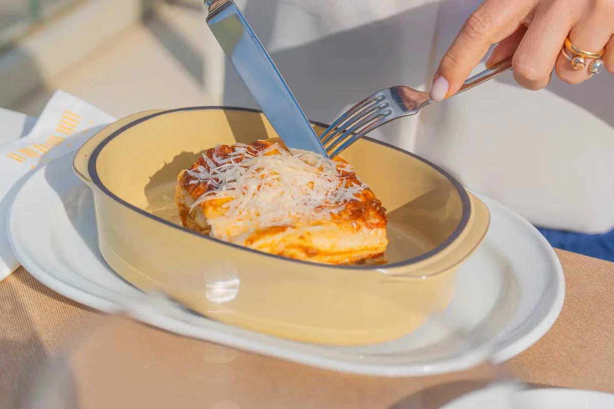 Porzione di lasagna con parmigiano grattugiato servita in pirofila