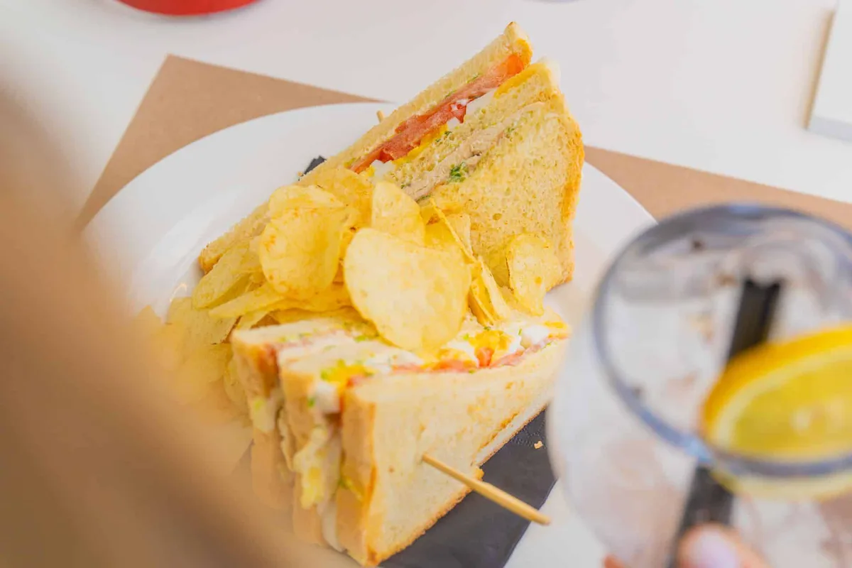 Club sandwich con patatine fritte servito nel piatto bianco