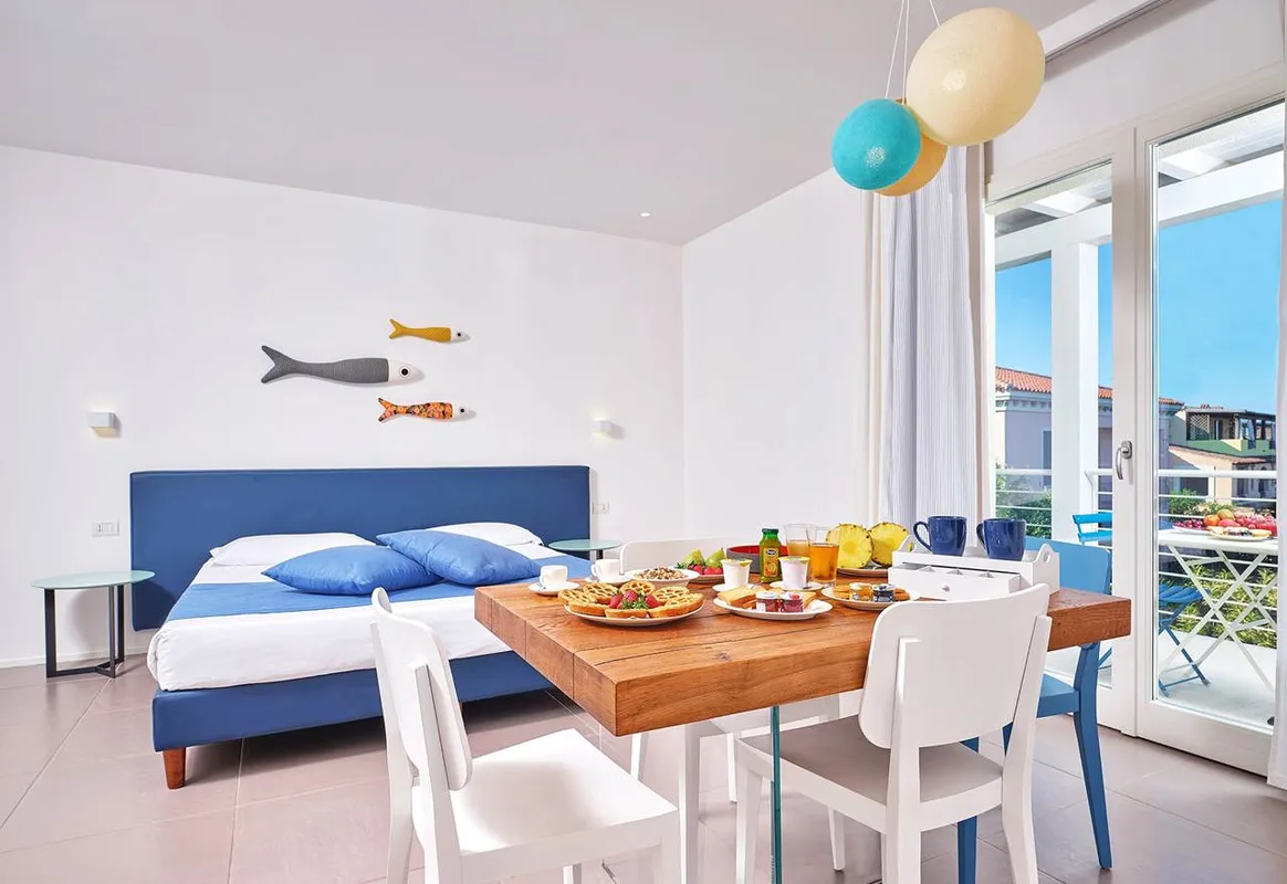 Camera con letto matrimoniale e tavolo apparecchiato per la colazione vicino al balcone