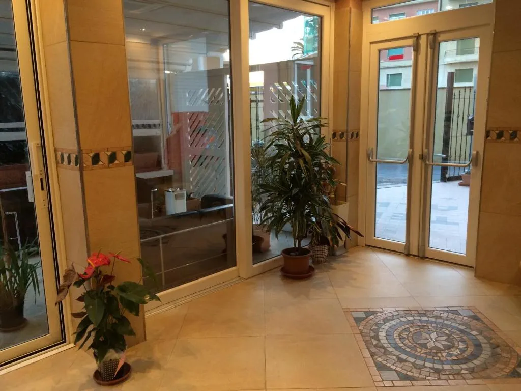 Ingresso interno dell'hotel con pavimento in marmo, mosaico e piante verdi