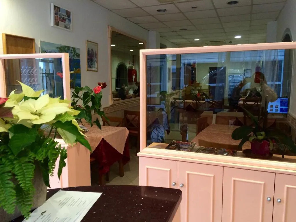 Sala da pranzo con tavoli apparecchiati, fiori e divisori in vetro