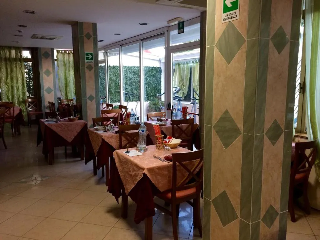 Sala ristorante con tavoli apparecchiati con tovaglie e vista sul giardino