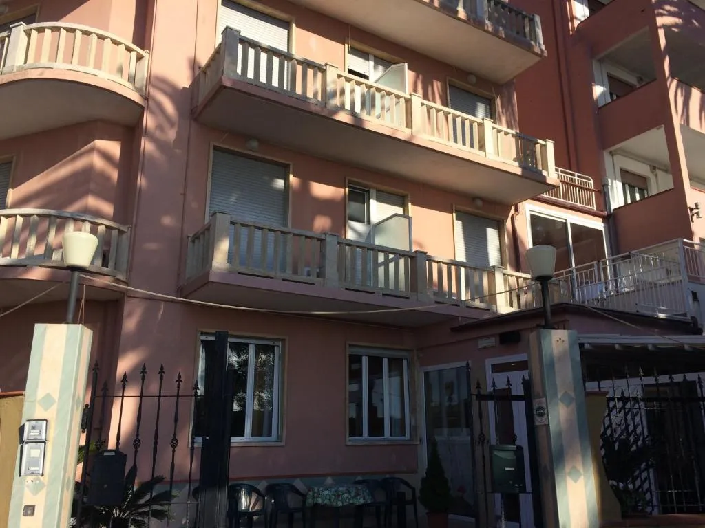 Facciata posteriore dell'edificio rosa con balconi e cancello in ferro battuto