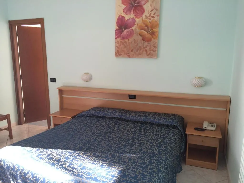Camera matrimoniale con letto, comodini, telefono e quadro floreale