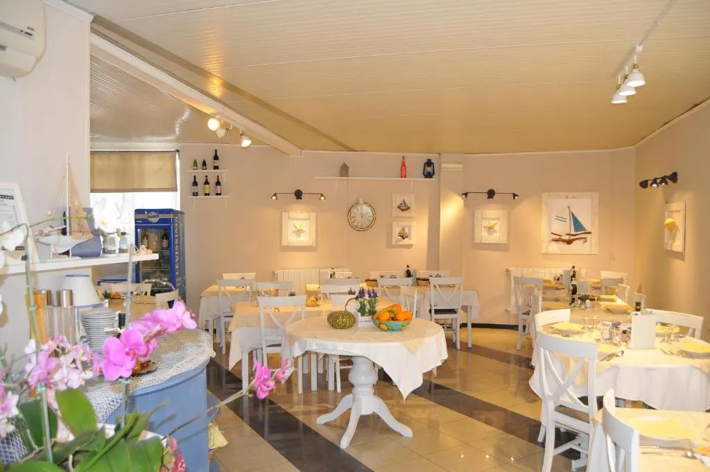 Sala colazione in stile marinaro con tavoli rotondi bianchi e decorazioni a tema nautico