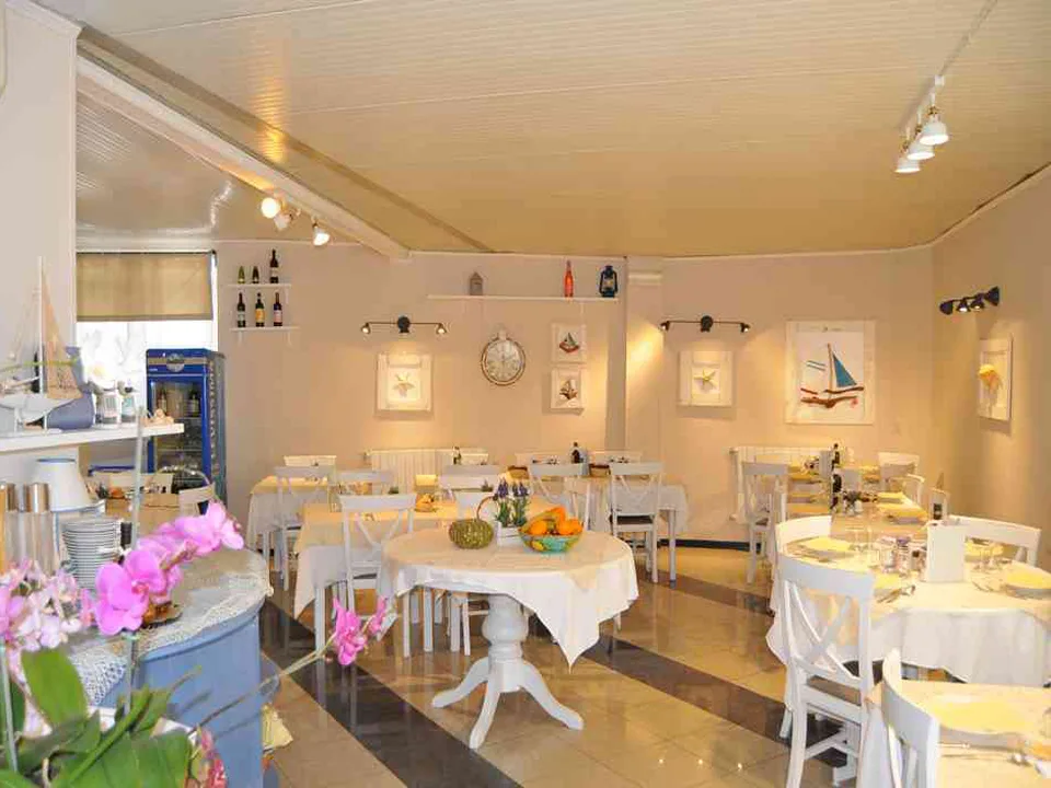 Sala da pranzo in stile mare con tavoli bianchi e decorazioni nautiche alle pareti
