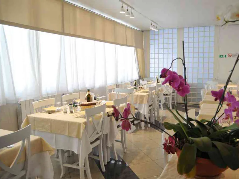 Ristorante con tavoli apparecchiati con tovaglie gialle e orchidee rosa in primo piano
