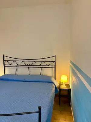 Camera da letto con letto matrimoniale, copriletto blu e parete decorata azzurra