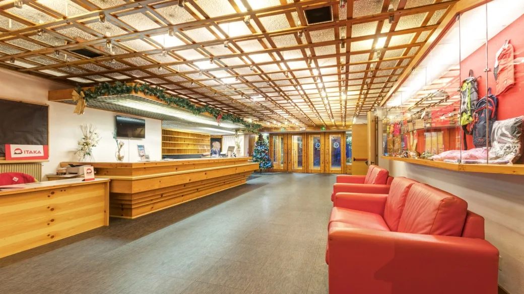 Reception dell'hotel con bancone in legno, divani rossi e decorazioni natalizie