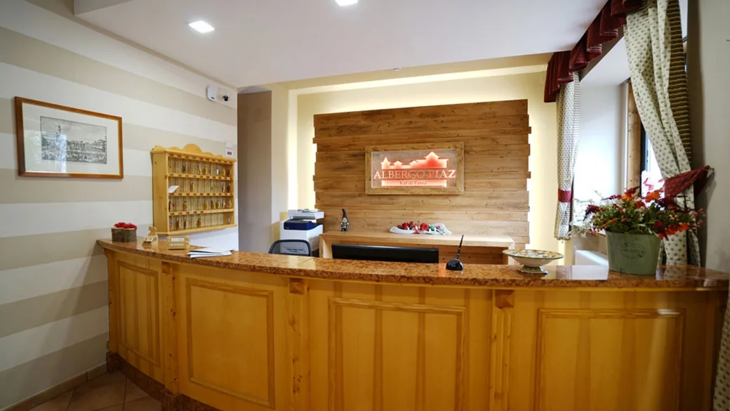 Reception dell'Albergo Piaz con bancone in legno e insegna dell'hotel