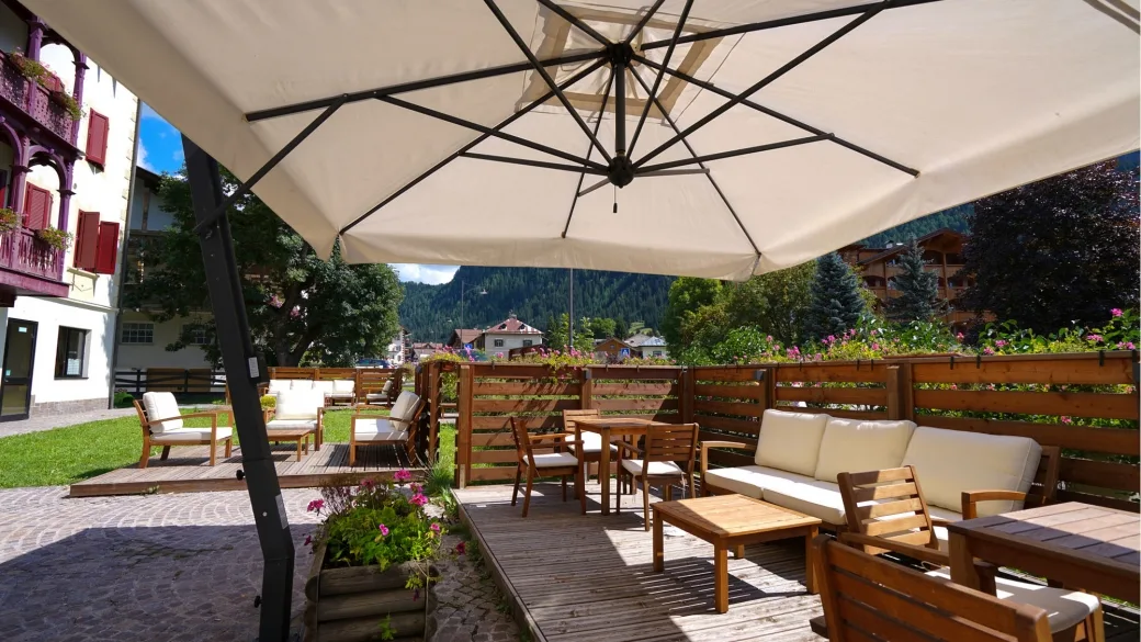 Terrazza esterna con divani in legno, ombrellone e vista sulle montagne