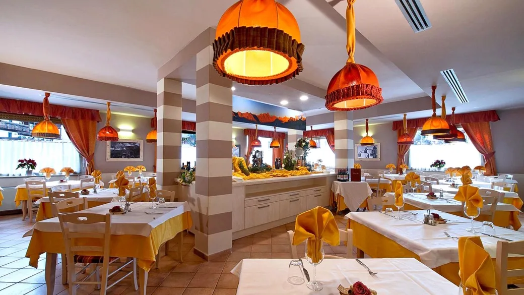 Sala ristorante elegante con lampade arancioni, tavoli apparecchiati e buffet centrale