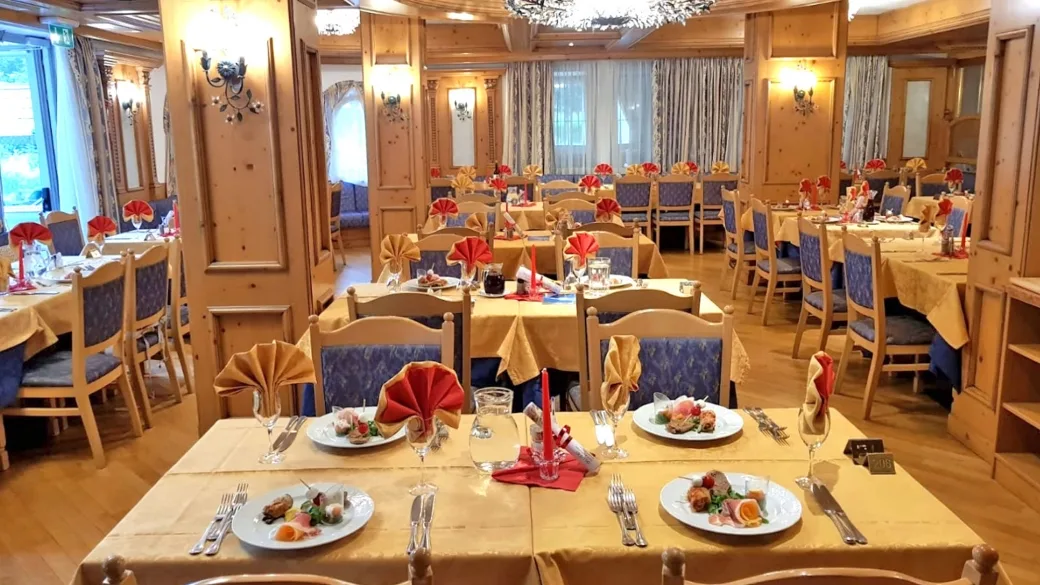 Sala ristorante con pareti in legno, tavoli apparecchiati con tovaglie gialle e tovaglioli decorati