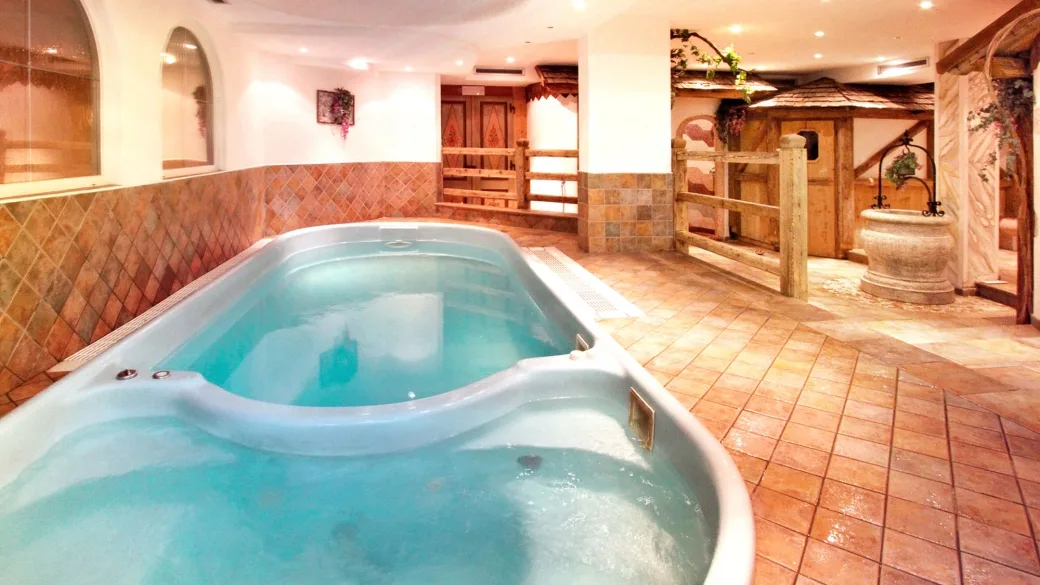 Vasca idromassaggio interna della spa con pavimento in cotto e arredi rustici in legno
