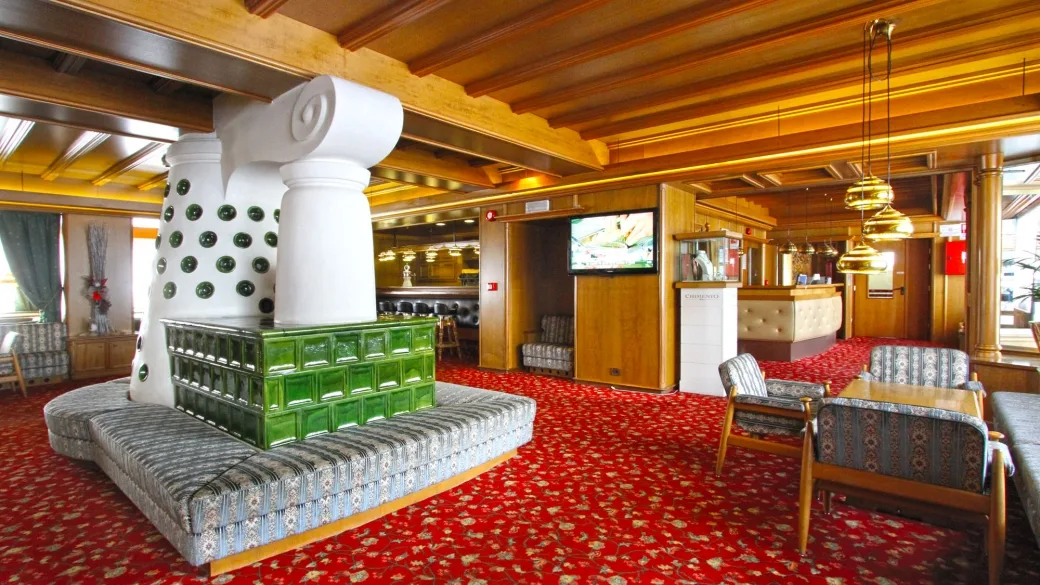 Hall dell'hotel con divani, poltrone, colonna decorativa in ceramica verde e area reception