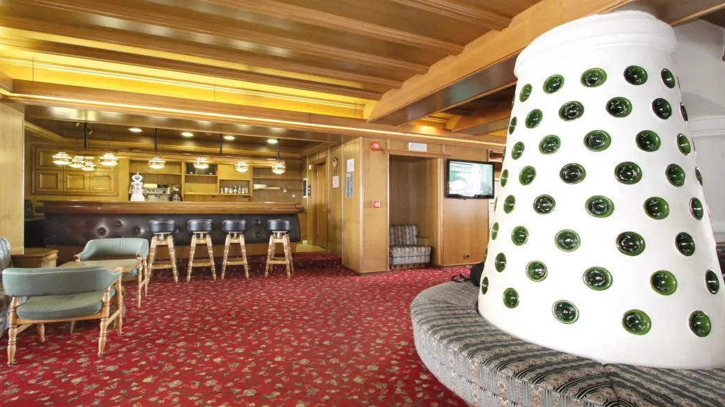 Zona lounge con bancone bar, sgabelli, poltrone e caratteristica colonna bianca decorata con inserti verdi