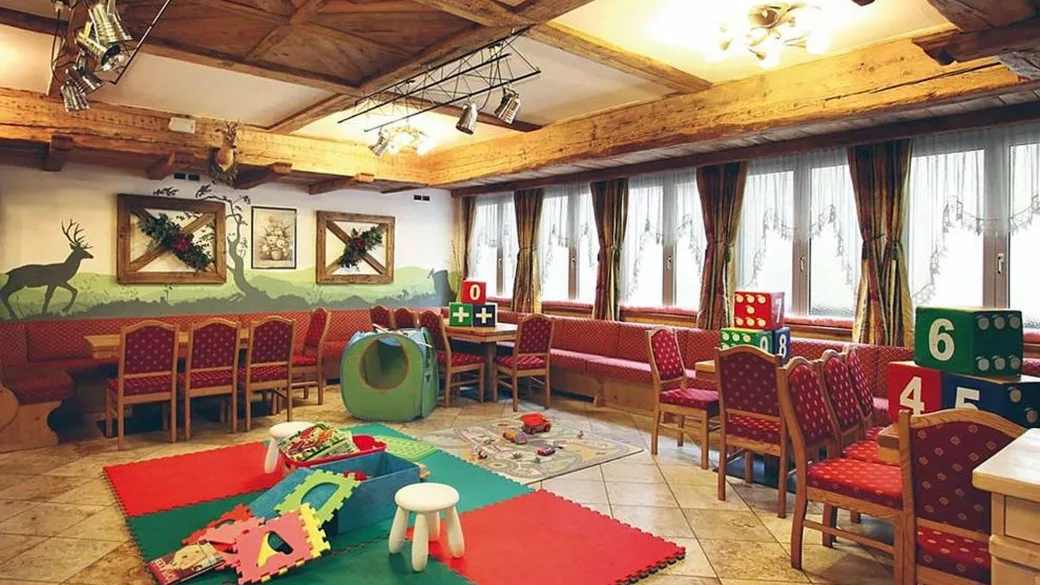 Sala giochi per bambini con tappeti colorati, giocattoli, cubi numerati e panche in legno