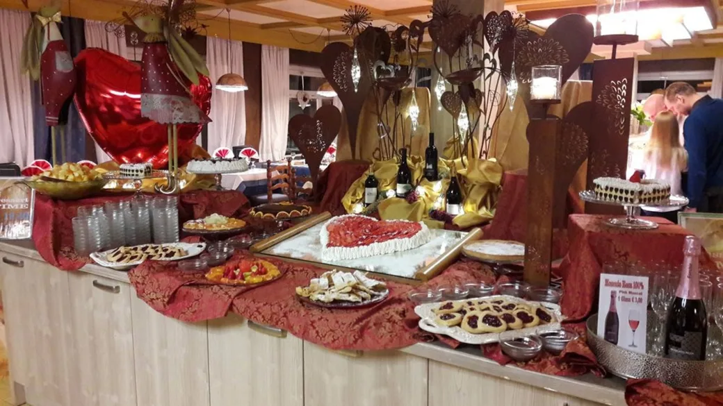 Buffet di dolci con decorazioni a tema cuori, torte, pasticcini e bottiglie di vino