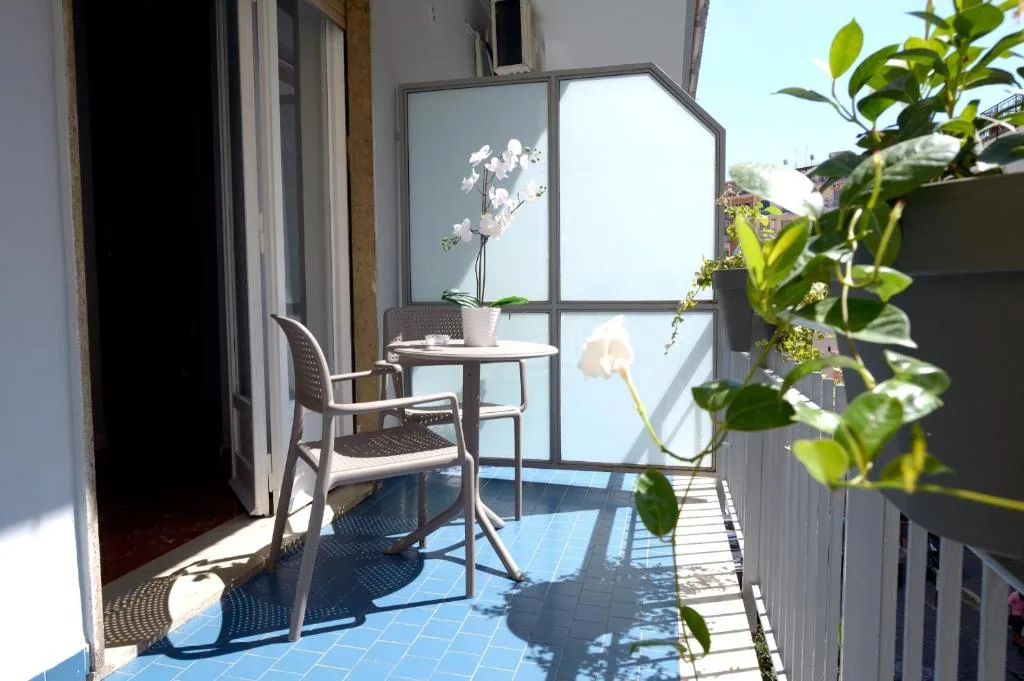Piccolo balcone con tavolino e sedia, orchidea bianca e piante verdi al sole