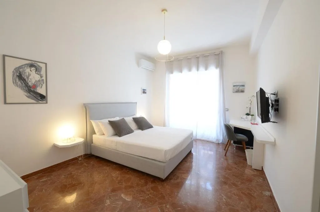 Camera matrimoniale con letto, scrivania, TV e pavimento in marmo lucido