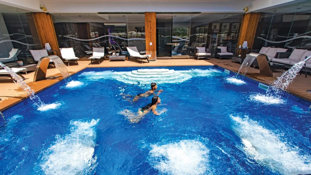 Piscina interna idromassaggio con cascate e lettini relax