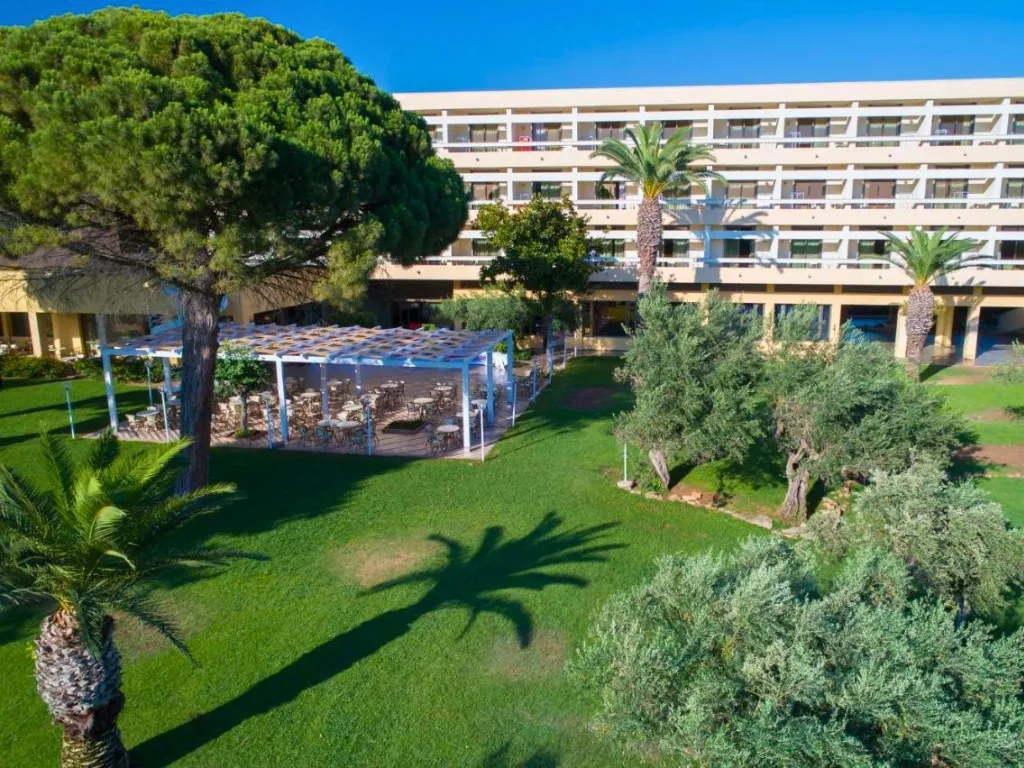 Giardino verde con pergolato e alberi davanti all'edificio dell'hotel