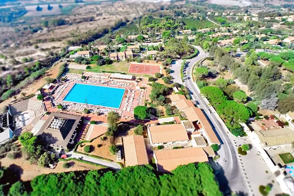 Veduta aerea del resort con grande piscina, campi sportivi e strutture immerse nel verde