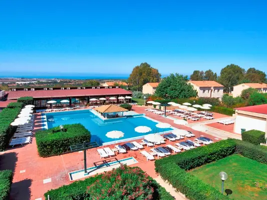 Vista panoramica della piscina circondata da lettini, siepi curate e vista sul mare