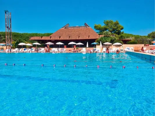 Grande piscina con acqua turchese e struttura con tetto a capanna in legno sullo sfondo