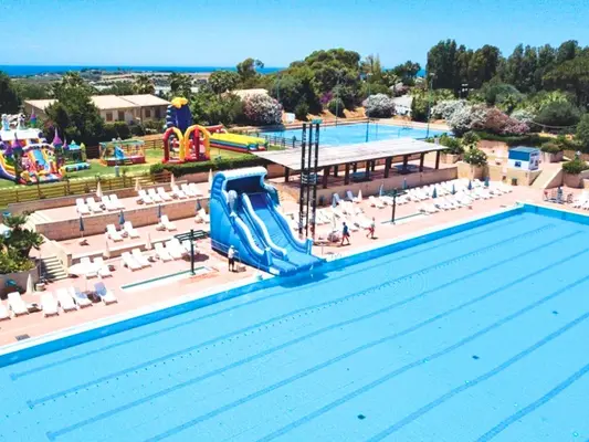 Piscina con scivolo gonfiabile, lettini e area giochi colorata per bambini vicino al mare