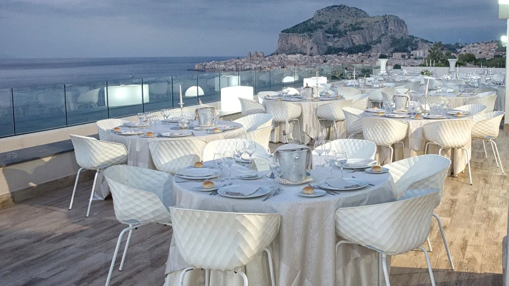 Ristorante panoramico in terrazza con tavoli allestiti e vista sul mare e la rocca di Cefalù