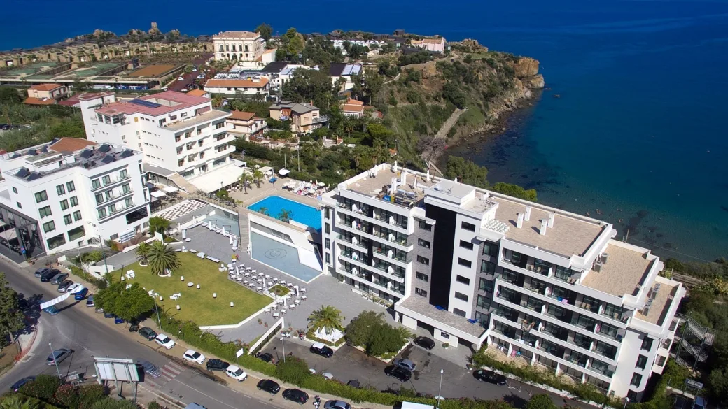 Vista aerea dell'hotel fronte mare con piscina, giardino e costa