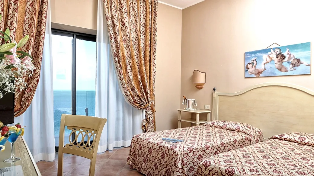 Camera dell'hotel con due letti, vista mare e arredi classici
