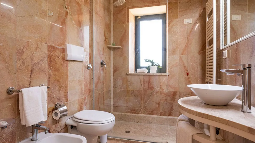 Bagno in marmo rosato con doccia, lavabo a bacinella e bidet