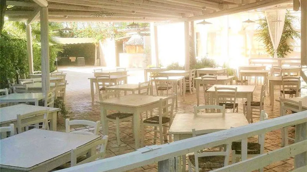 Terrazza ristorante esterna con tavoli e sedie in legno chiaro