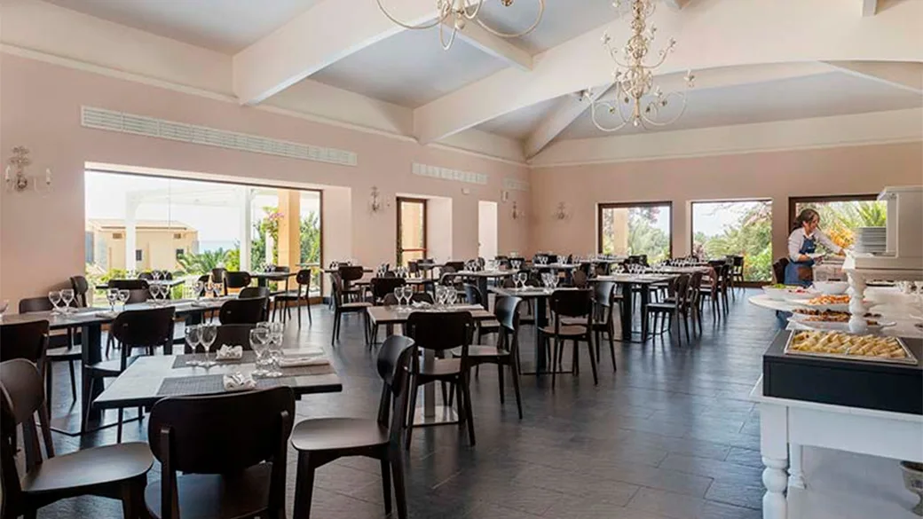 Sala ristorante con tavoli apparecchiati, lampadari e grandi finestre