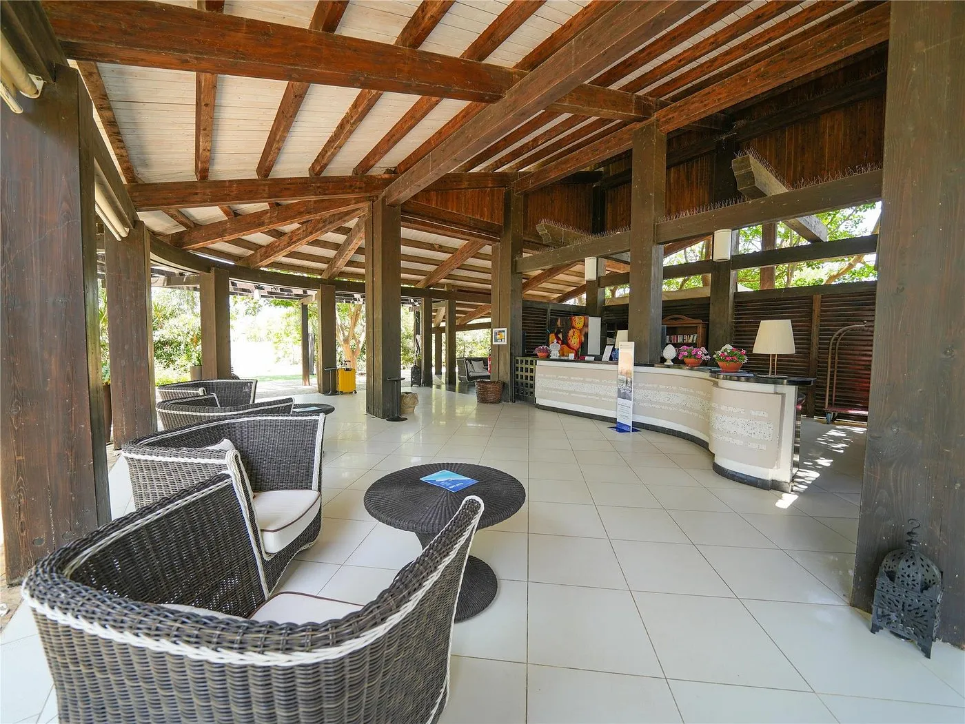 Reception all'aperto con struttura in legno e poltrone in rattan