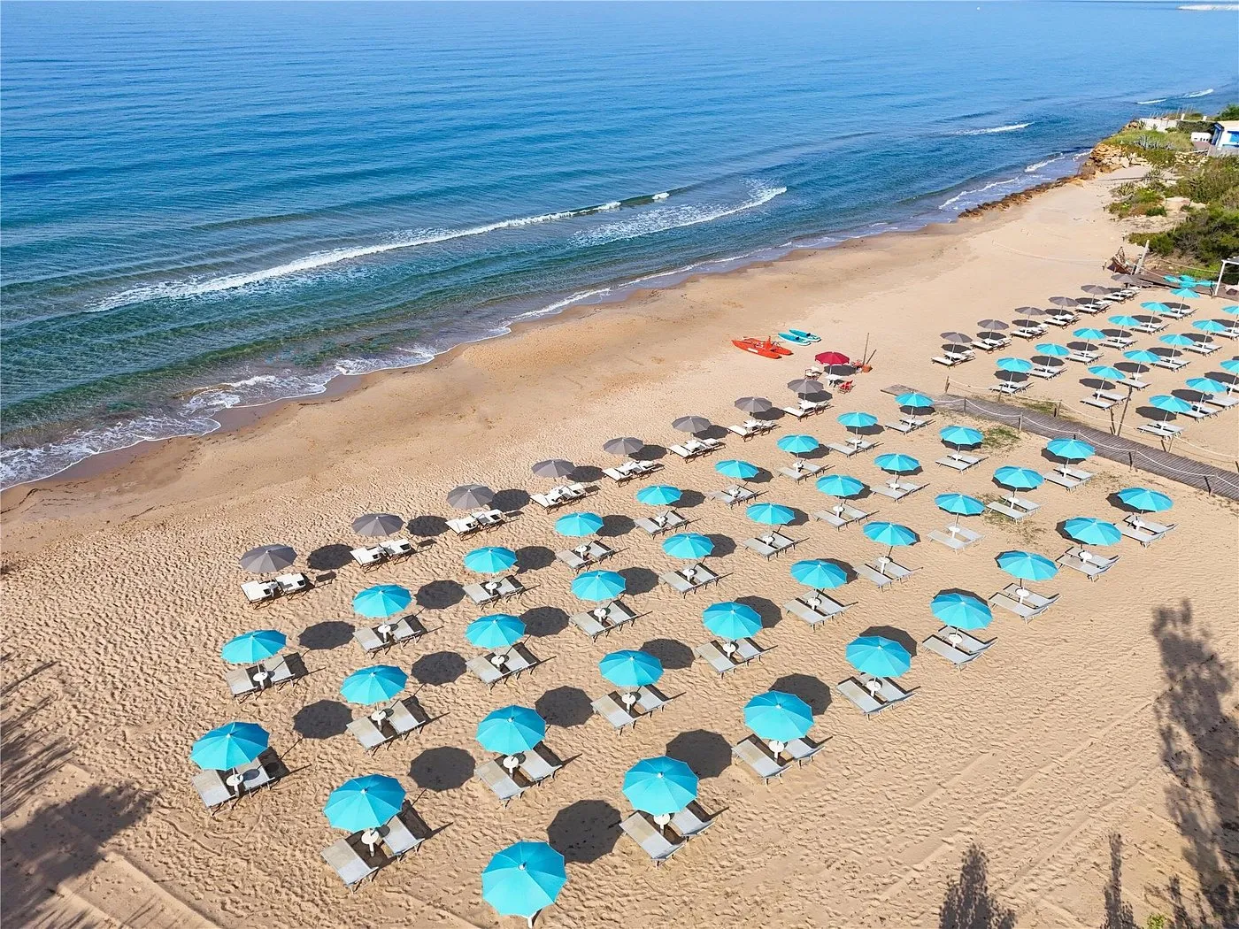 Vista aerea della spiaggia sabbiosa con file di ombrelloni azzurri