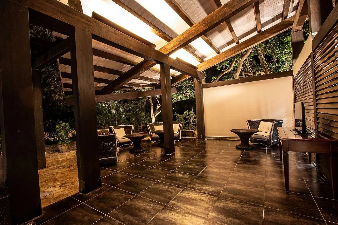 Area relax notturna con pergolato in legno e poltrone in rattan
