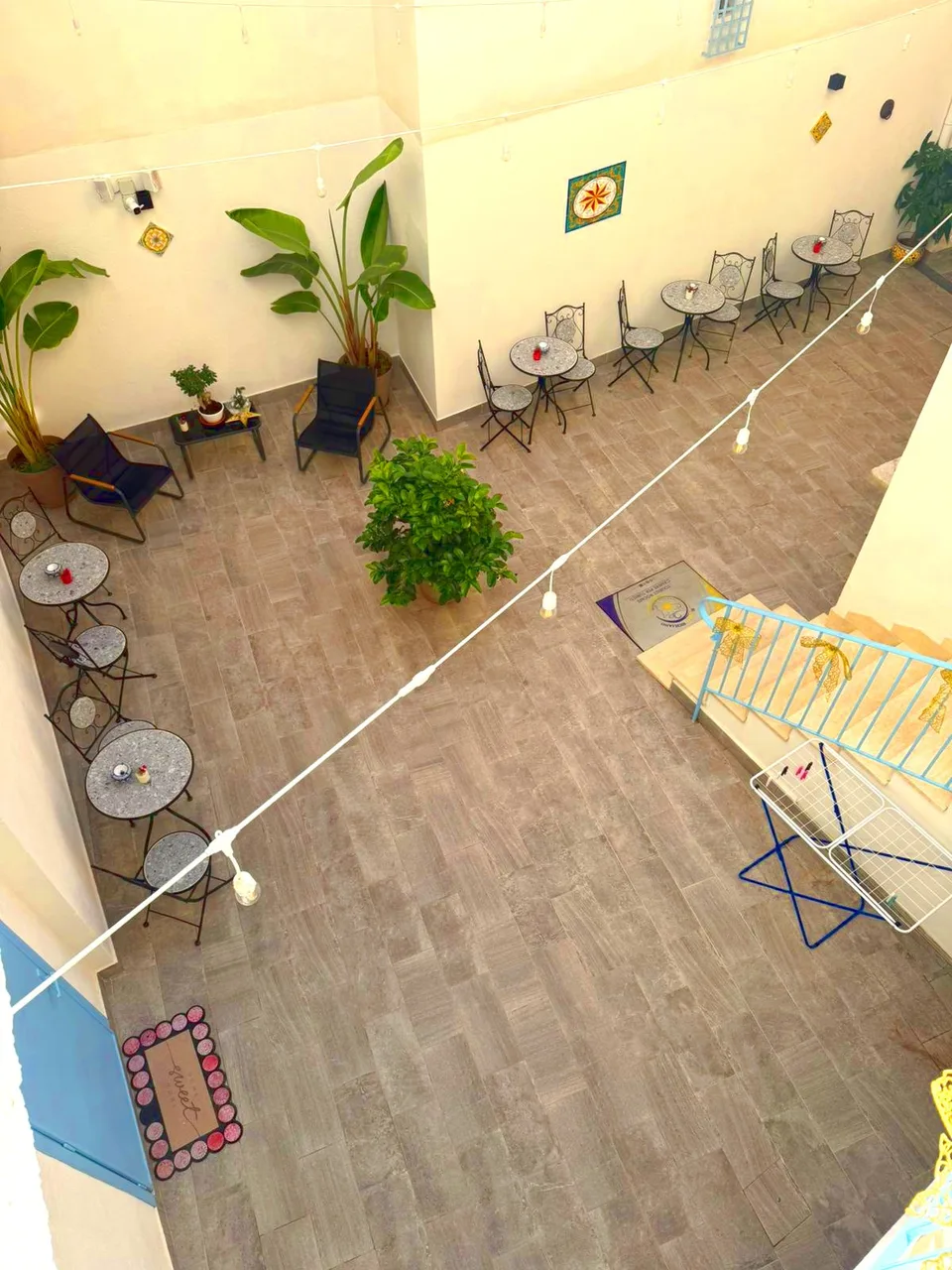 Vista dall'alto del cortile interno con tavolini, piante e scala azzurra