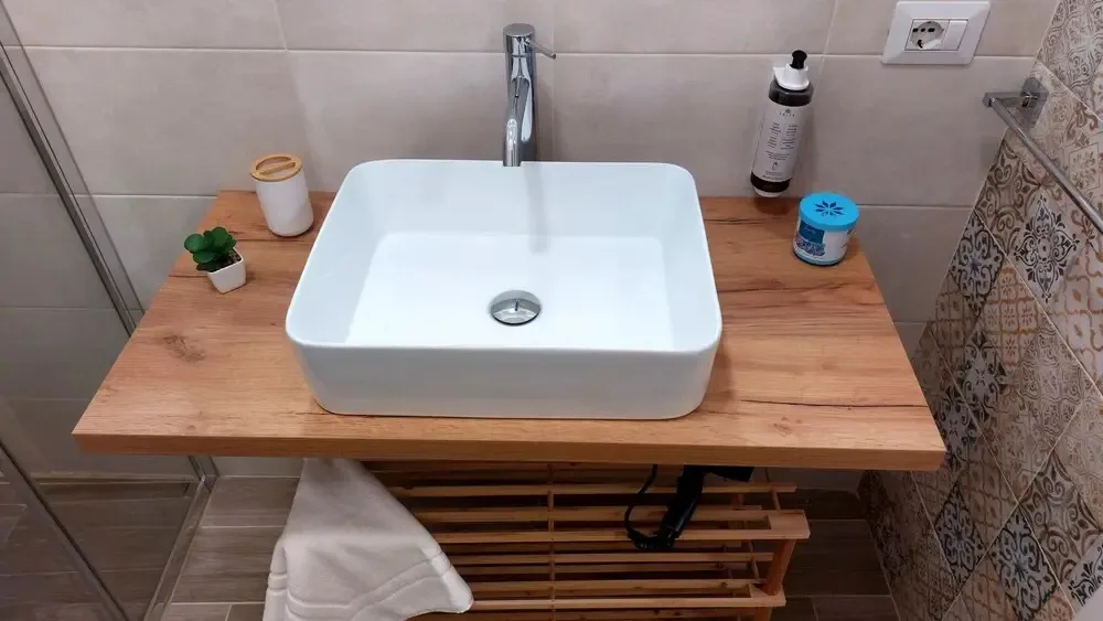 Lavabo rettangolare bianco su piano in legno con rubinetto cromato