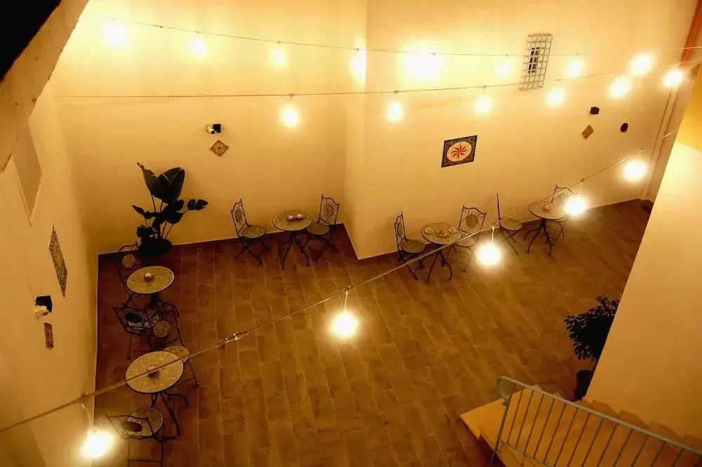 Cortile interno con tavolini in ferro battuto, luci decorative e piante