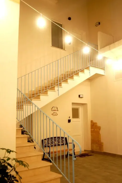 Scala interna con ringhiera azzurra e luci decorative a parete